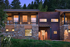 front entry of stone and steel contemporary luxury mountain home at twilight