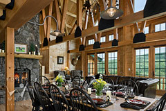 dining room of milled log home with trusses towards fireplace living room and windows