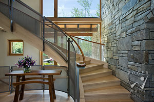 vignette of contemporary curved stairway with wire mesh and wood railing