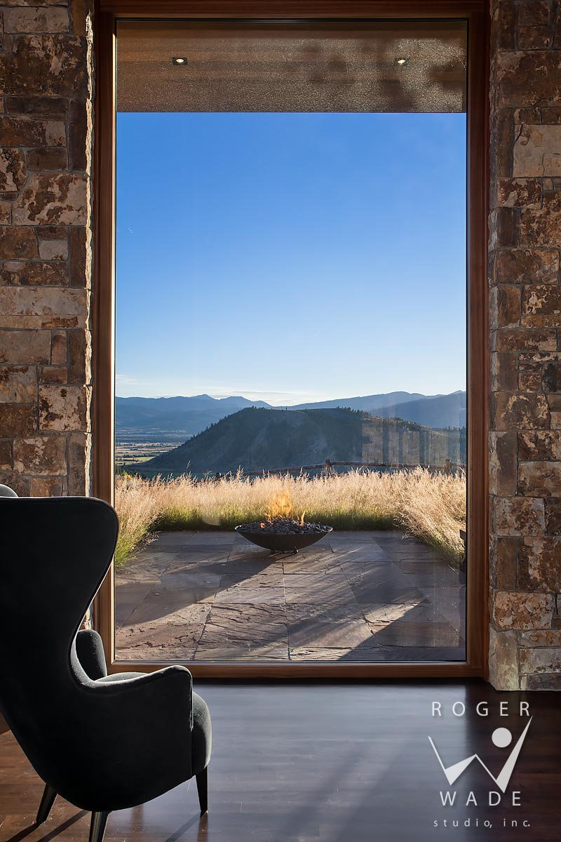 contemporary architectural stock photography, looking out window toward patio with fire pit and mountain view, jackson, wy