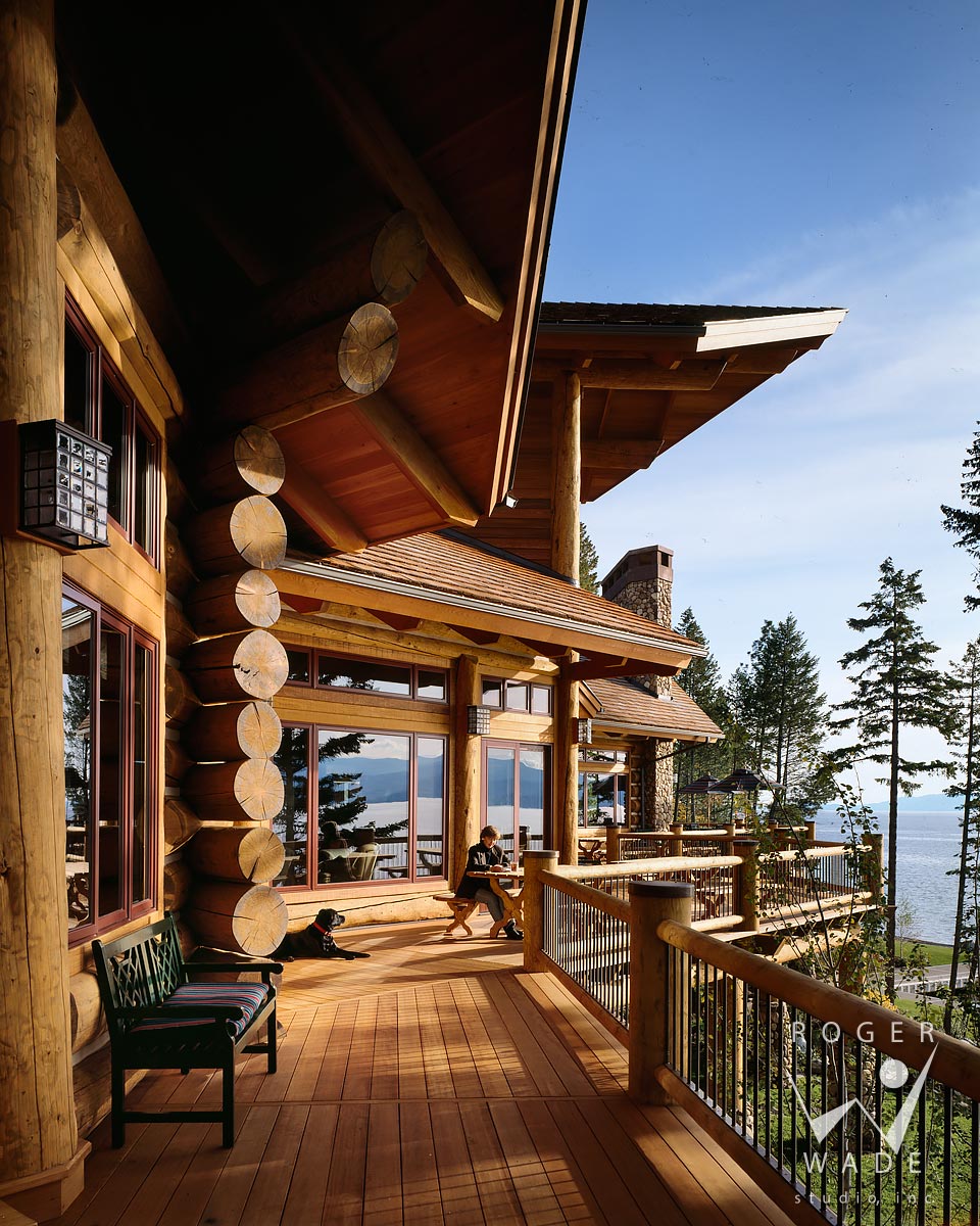log home, deck detail with woman and dog, looking out to view of flathead lake, woods bay, mt