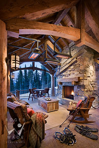 rustic timber covered patio with stone fireplace of luxury mountain home during winter